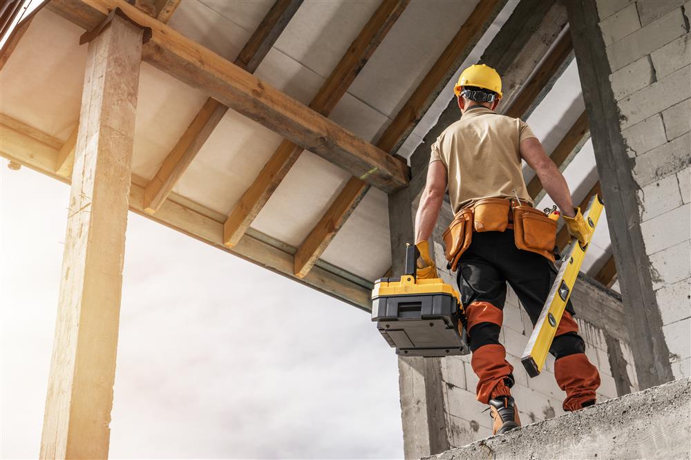 Un ouvrier sur un chantier de construction, équipé d’outils, illustrant le travail nécessaire pour choisir la bonne porte selon le type de projet résidentiel, commercial ou multi-logement.